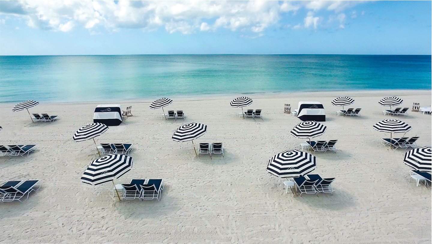 Black and white lounge chairs on the beach by the ocean