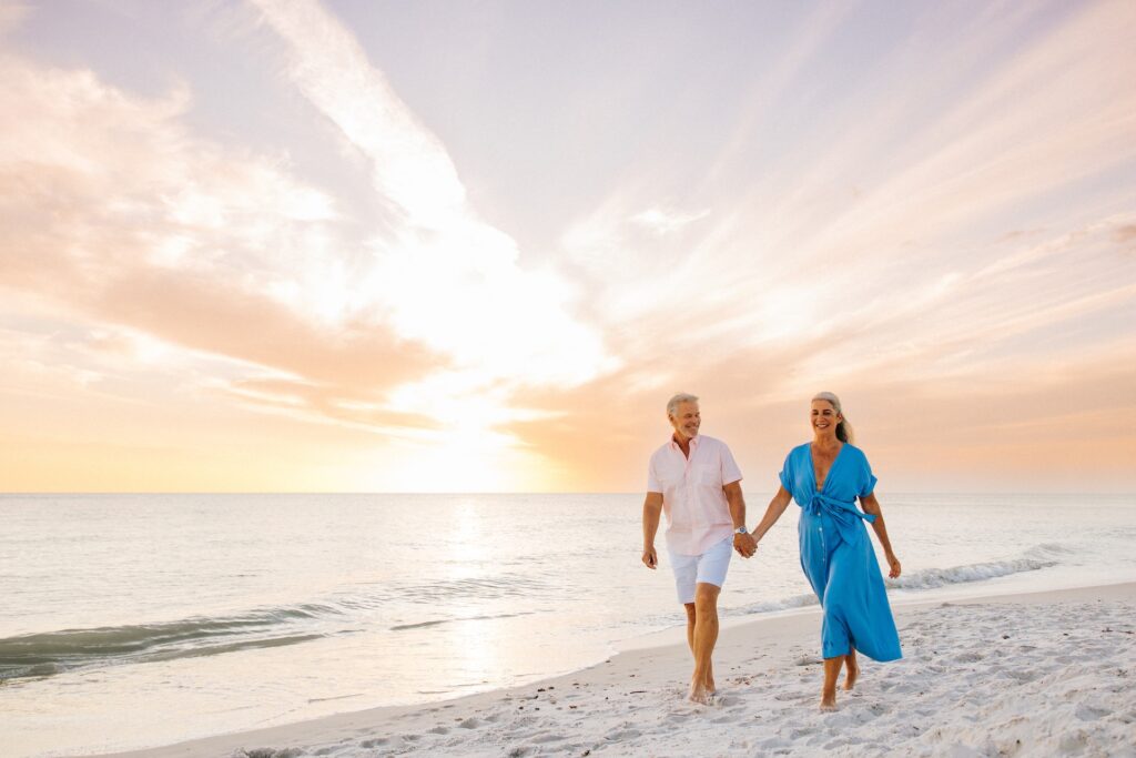 older couple walking to sunset on beach