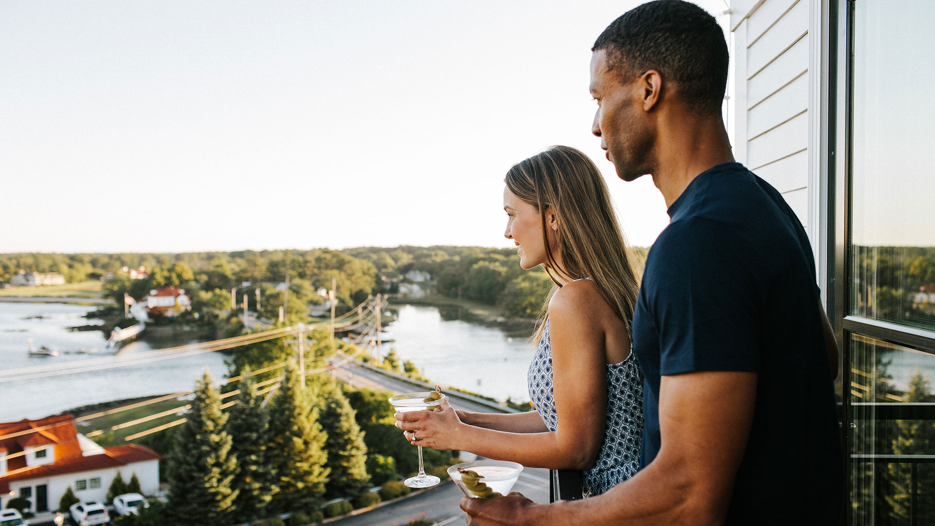 A couple looks out over the harbor on a balcony.