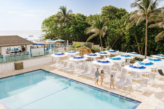 A family walks along the pool at Jupiter Beach Resort in Jupiter, Florida.
