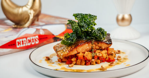 A grilled salmon fillet sits on a bed of diced vegetables at Ringside, Cirque St. Armand's signature Sarasota restaurant.