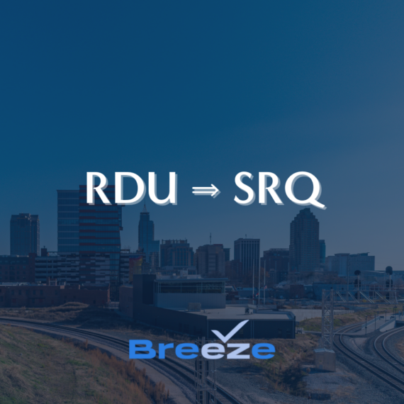 View of a city skyline with industrial tracks in the foreground. Text on the image reads RDU ➔ SRQ and Breeze, indicating a travel or flight route. The sky is clear and blue.