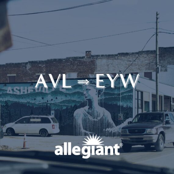 View of a city street with cars and a building featuring a mural of a person and forest. Overlaid text reads AVL ⇒ EYW and allegiant with a sunburst logo.