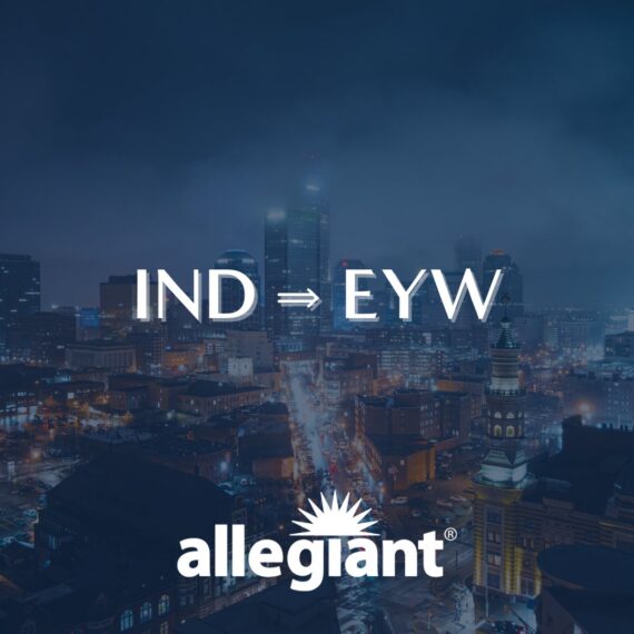 Nighttime cityscape with tall buildings and streetlights. Overlaid text reads IND ⇒ EYW and allegiant with a sunburst logo, promoting a flight route from Indianapolis to Key West by Allegiant airline.