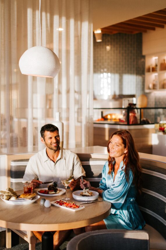 A couple sits at a round restaurant table enjoying a meal together.