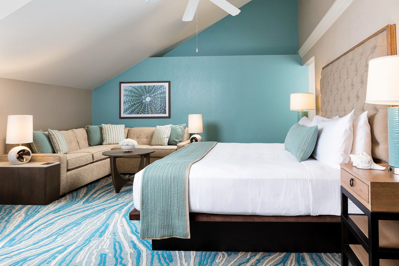 A wide view of a hotel room with a bed, sofa, and coffee table.