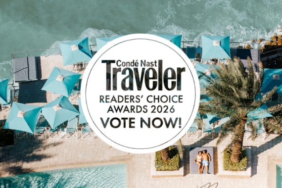 Aerial view of turquoise poolside umbrellas by the ocean at Clearwater Beach, with two people lounging on deck chairs. A circular overlay reads, “Condé Nast Traveler Readers’ Choice Awards 2026. Vote Now!”.