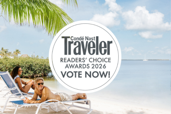 Two people relax on lounge chairs by a calm beach under palm trees, with a Condé Nast Traveler Readers’ Choice Awards 2026 “Vote Now!” graphic in the center.