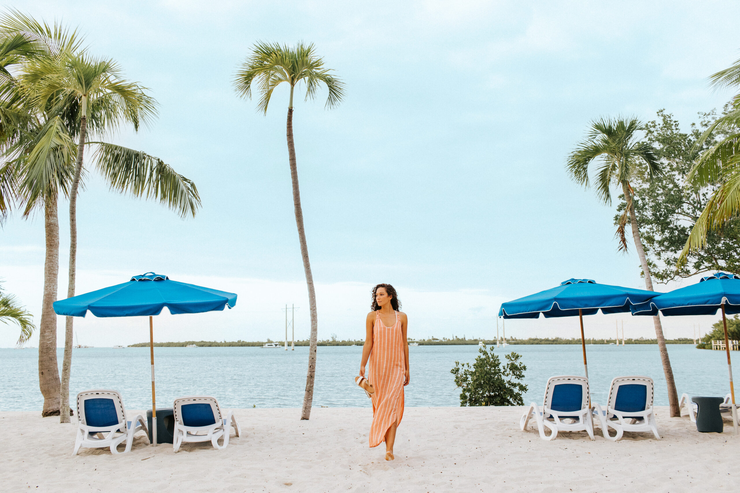 woman on the beach walking with sandals in hand