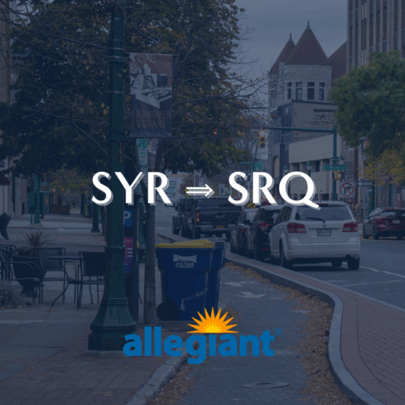 Downtown city street with parked cars and autumn trees. Text reads SYR ⇒ SRQ above the Allegiant logo, indicating a flight route between Syracuse and Sarasota.
