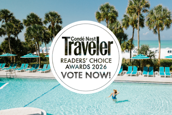 A woman swims in a clear pool surrounded by palm trees, lounge chairs, and umbrellas near a beach. An overlay reads: Condé Nast Traveler Readers Choice Awards 2026 Vote Now!.