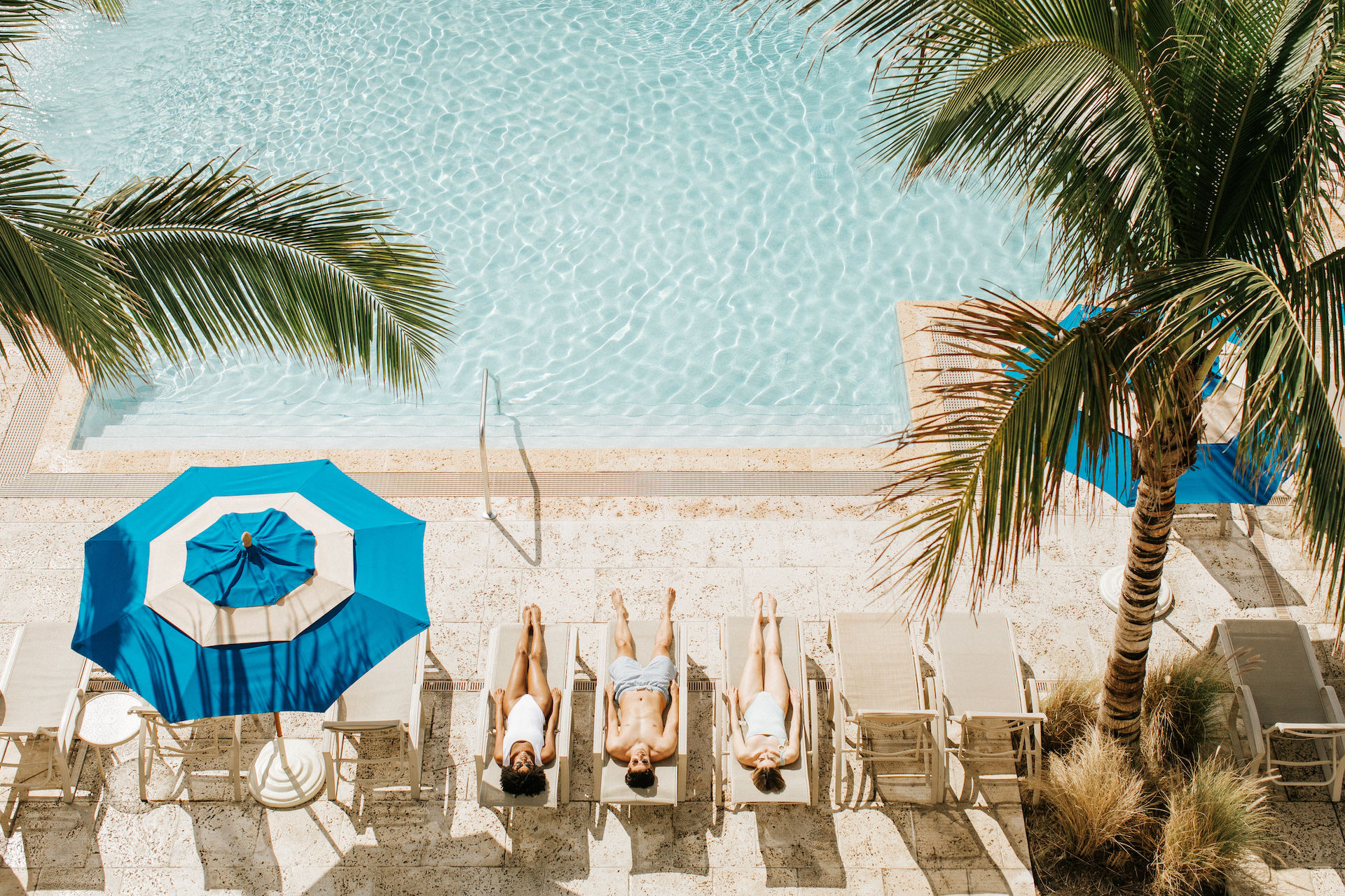 aerial view of three people laying out by the pool