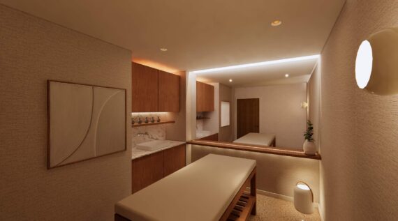 A modern spa treatment room with a cushioned massage table, wooden cabinets, a large wall mirror, soft lighting, artwork on the wall, and neutral beige tones for a calming atmosphere.