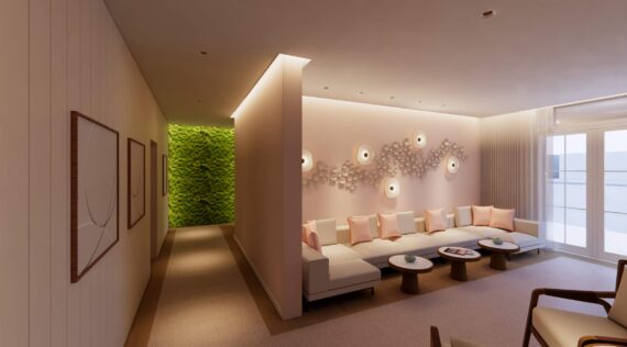 A modern lounge with a curved white sofa, pink cushions, round coffee tables, soft wall lights, abstract wall art, and a hallway with a bright green vertical plant wall in the background.