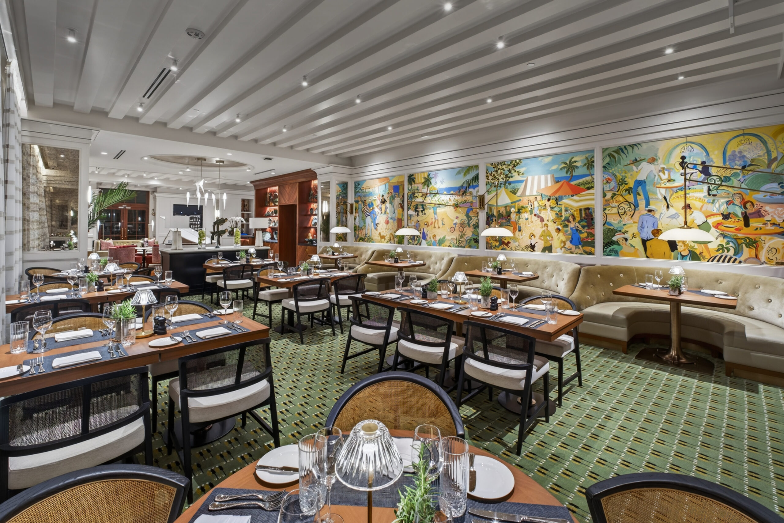 A stylish restaurant dining room with neatly set tables, cushioned chairs, and a long mural depicting colorful outdoor scenes on the wall. The space is bright, elegant, and inviting with green carpeting and modern lighting.