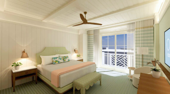 A bright, airy hotel room with a double bed, pastel bedding, bedside tables, a ceiling fan, TV, large window with sheer curtains, armchair, bench, and light-colored décor with green and peach accents.