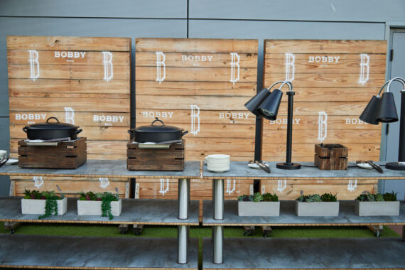 Catering set up at Rooftop Lounge for an event with wooden boards featuring the Bobby logo as the backdrop.