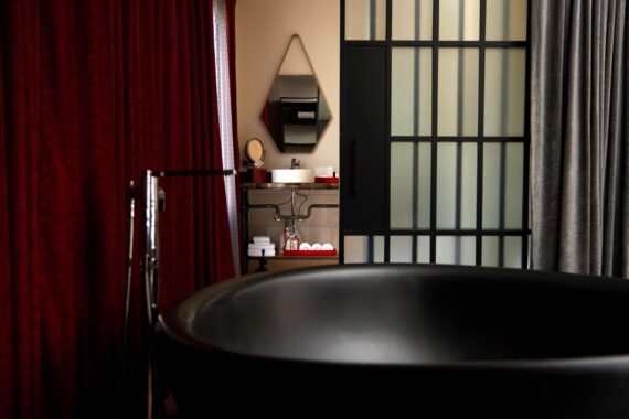 Black bathtub hidden behind a velvet curtain in the bathroom of a suite at Bobby Nashville.