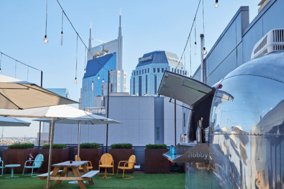 The bar, various seating options, and string lighting atop the Rooftop Lounge at Bobby Nashville.