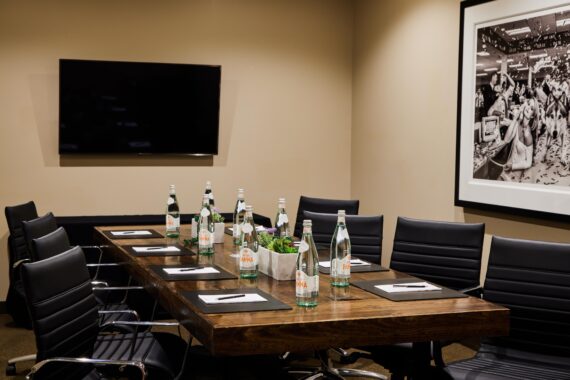 Boardroom with waters, notebooks, a mounted TV, and artwork on the walls at Bobby Nashville.