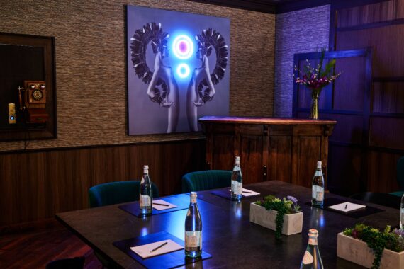 Dark and moody meeting space at Bobby Nashville featuring neon lighting and artwork on the walls.