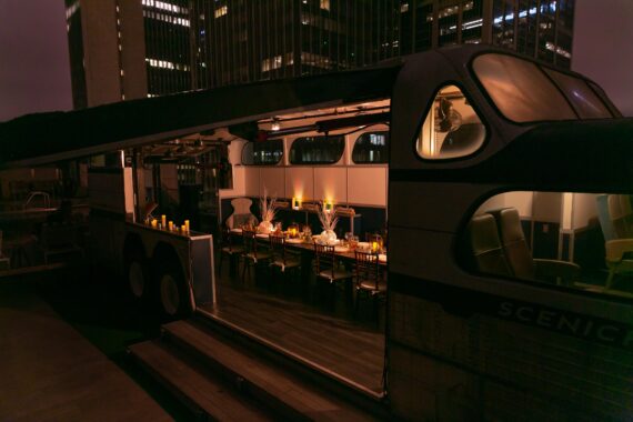 Nighttime shot of a lit-up function table inside the Greyhound Scenicruiser bus atop Bobby Hotel's rooftop in Nashville.