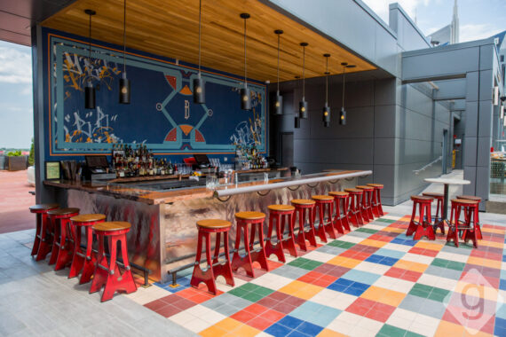 Rooftop Lounge at Bobby Nashville featuring the bold and colorful bar with red barstools and playful designs.