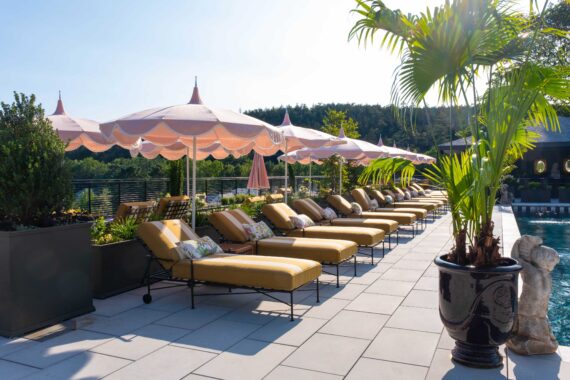 A row of cushy loungers and umbrellas surrounding the pool at The Asticou.