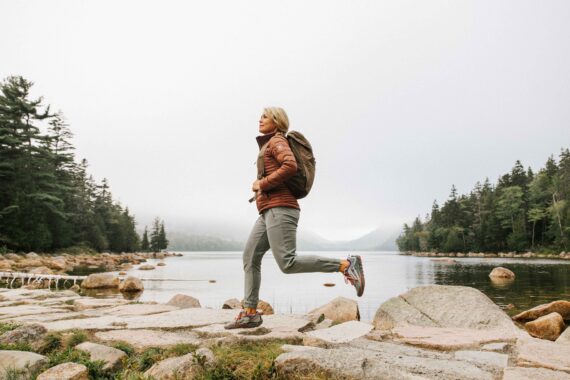 A woman ventures through Acadia National Park with the Bubble Mountains in the background.