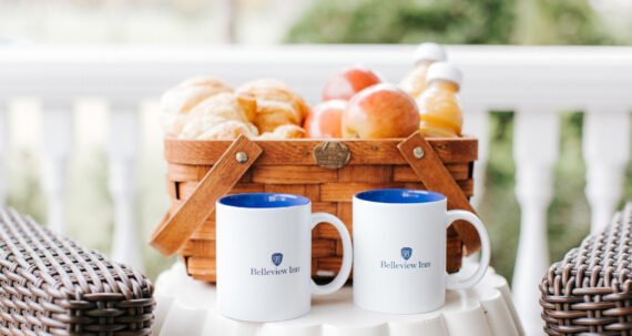 Basket with fruit and two logo coffee mugs in front