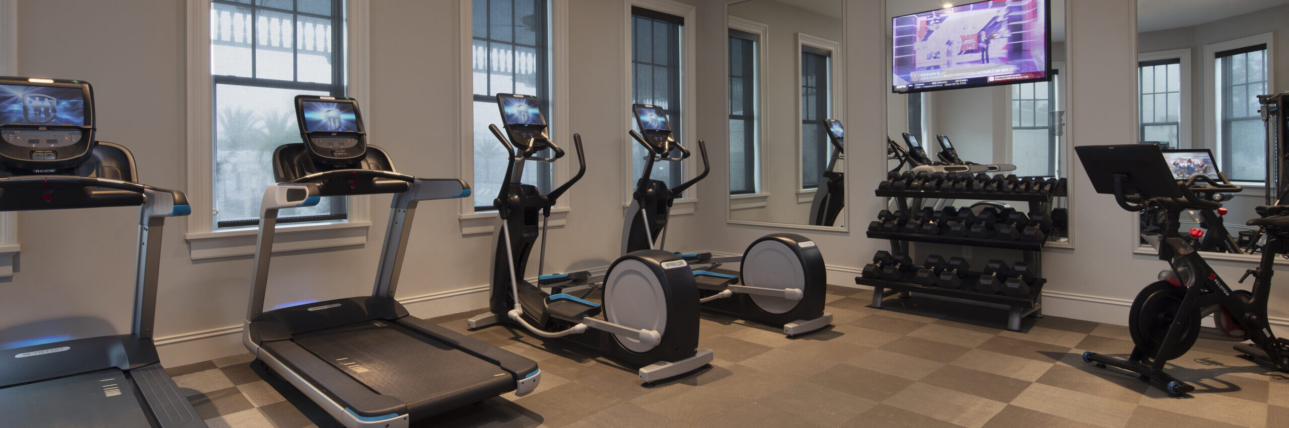 interior of a gym. treadmills, elypticals, free weights and a stationary bicycle