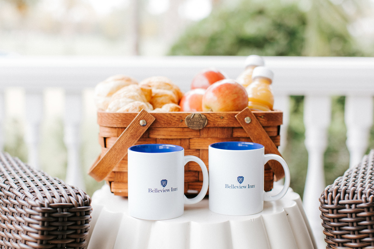 belleview inn mugs with a basket of apples, juice, and croissants