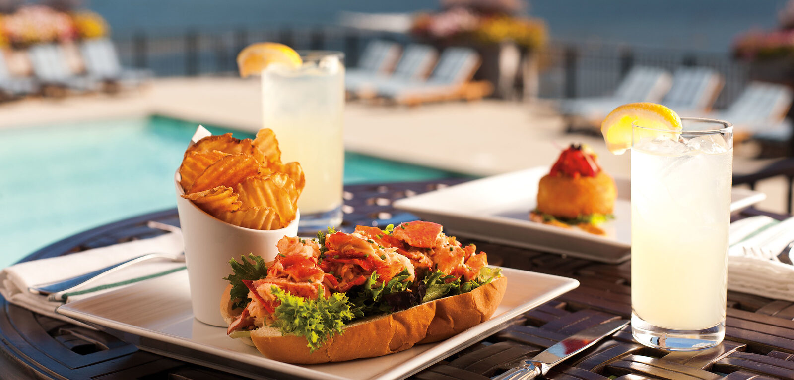 lobster roll with a side of chips by the pool